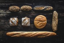 Плоская кладка из золота ассортимент домашнего хлеба на темном деревянном фоне — стоковое фото