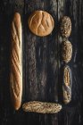Flache Lage des Goldsortiments hausgemachtes Brot auf dunklem Holzgrund — Stockfoto