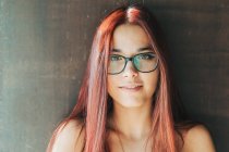 Zufriedener stilvoller Teenager mit Brille an der braunen Wand und Blick in die Kamera — Stockfoto