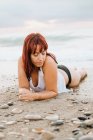 Mujer jengibre relajándose en la playa al atardecer - foto de stock