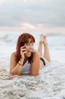 Імбирна жінка розслабляється на пляжі під час заходу сонця — стокове фото