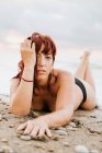 Mujer desnuda acostada cerca de las olas del mar - foto de stock