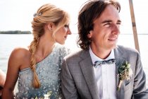 Soddisfatti amanti sposati in abiti da sposa rilassante in barca con mare sullo sfondo — Foto stock