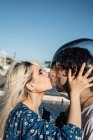 Side view of attractive blond female with closed eyes licking transparent round aquarium on head of adult man — Stock Photo