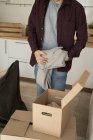 Hombre irreconocible sacando suéter gris suave de cajas en la cocina - foto de stock