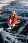 Woman sitting on frozen river and tying the shoelaces — Stock Photo