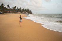 Женщина в пляжной одежде ходит босиком по песку — стоковое фото