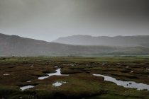 Autumn valley covered with water patches after rain surrounded by foggy hills in Scotland — Stock Photo