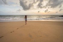 Женщина в пляжной одежде ходит босиком по песку — стоковое фото