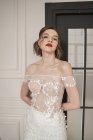 Prachtvolle nachdenkliche junge Braut im weißen Spitzenkleid blickt in die Kamera und grübelt — Stockfoto