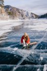 Donna seduta sul fiume ghiacciato e legare i lacci delle scarpe — Foto stock