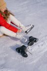 Mulher sentada na neve e trocando botas — Fotografia de Stock