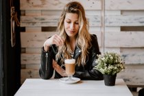 Longo cabelos na moda bela mulher loira bebendo de um copo de delicioso café espumoso com olhos fechados — Fotografia de Stock