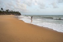 Donna in beachwear che cammina sulla sabbia a piedi nudi — Foto stock