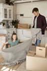 Jovem casal feliz tirando suéter cinza macio e cobertor de caixas na cozinha — Fotografia de Stock