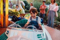 Joyeux garçon chevauchant carrousel sur le terrain de foire — Photo de stock
