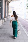 Vue arrière de l'élégante femme d'affaires confiante marchant dans la rue, portant un sac à main — Photo de stock