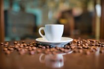 Керамические чашки и кофейные зерна на деревянном столе — стоковое фото