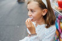 Cheerful girl eating cotton candy on street — Stock Photo