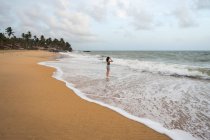 Femme en tenue de plage marchant sur sable pieds nus — Photo de stock