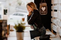 Vista lateral de cabelos longos na moda bela mulher loira sentada em uma loja de café com olhos fechados — Fotografia de Stock