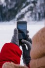 Imagem cortada de mulher tirando fotos de montanhas nevadas com smartphone — Fotografia de Stock