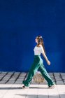 Giovane donna di tendenza felice camminando in città contro la porta blu — Foto stock