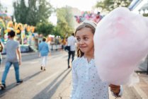 Cheerful girl eating cotton candy on street — Stock Photo