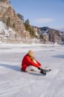 Mujer sentada en la nieve y cambiando botas - foto de stock