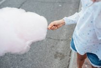 Веселая девушка ест сахарную вату на улице — стоковое фото