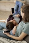 Ruhige nachdenkliche junge Mann und Frau auf gemütlichen Sofa liegend und surfende Mobiltelefone zu Hause — Stockfoto
