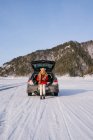 Woman sitting on car trunk in snowy valley — Stock Photo