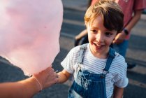 Cheerful boy taking candyfloss from vendor — Stock Photo