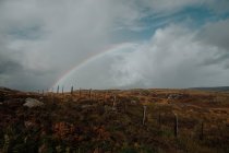Paisaje de otoño Campo escocés con cerca vieja y arco iris piercing cielo nublado - foto de stock