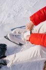 Abgeschnittenes Bild einer Frau, die auf Schnee sitzt und Stiefel wechselt — Stockfoto