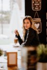 Vista lateral de cabelos longos na moda bela mulher loira bebendo de um copo de café espumoso delicioso enquanto olha para a câmera — Fotografia de Stock