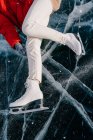 Abgeschnittenes Bild einer Frau auf Schlittschuhen, die auf Eis liegt — Stockfoto