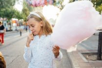Ragazza allegra mangiare zucchero filato sulla strada — Foto stock