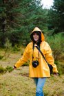 Mulher no capuz e capa de chuva amarela andando i floresta — Fotografia de Stock