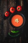 Hausgemachtes typisch spanisches Gazpacho von oben. Salmorejo. Tomatensuppe mit Gurken; Grüner Pfeffer, Brot und Olivenöl auf dunklem Holzgrund. Spanisches Essen. Flache Lage. — Stockfoto