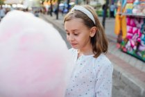Fröhliches Mädchen isst Zuckerwatte auf der Straße — Stockfoto