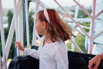 Cheerful girl riding Ferris wheel with parent — Stock Photo