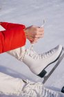 Abgeschnittenes Bild einer Frau, die auf Schnee sitzt und Stiefel wechselt — Stockfoto