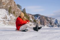 Femme assise sur la neige et changer de bottes — Photo de stock