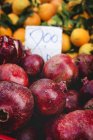 Stand lleno de granadas orgánicas maduras y naranjas con etiqueta de precio en el mercado de agricultores al aire libre - foto de stock