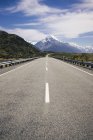 Asphaltstraße und tropisch grüne Klippen und blauer See mit wolkenlosem blauem Himmel und Bergkoch in Neuseeland — Stockfoto