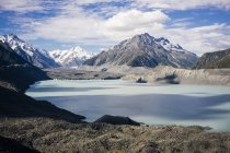 Costa rocosa del lago con cielo azul y montaña Cook en Nueva Zelanda - foto de stock