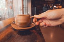 Persona de la cosecha sosteniendo taza de café en la mesa - foto de stock