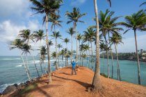 Hombre entre palmeras a orillas del mar - foto de stock