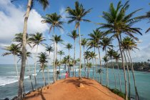 Tranquil female traveler among palms at seashore — Stock Photo